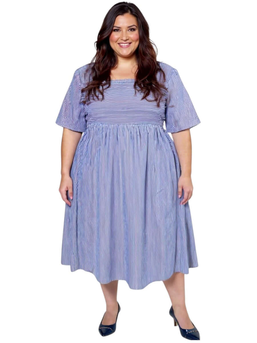 Plus size woman wearing Dale and Waters August Dress in blue print with shirred bodice and side pockets.