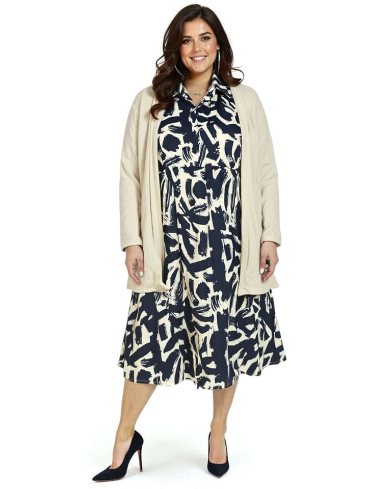 Plus size woman in a black and cream print Johanna dress by Dale and Waters, wearing a light cardigan and heels.