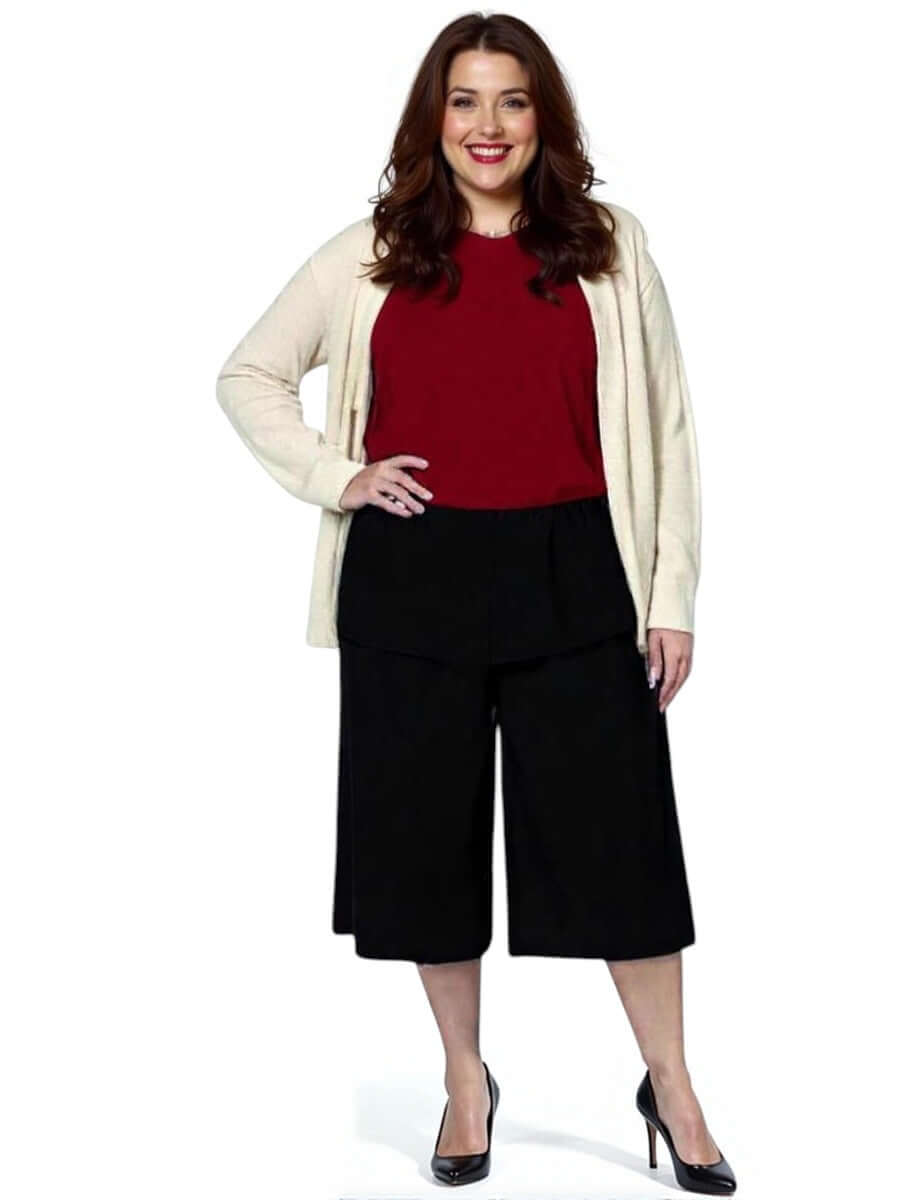 Women’s plus size model wearing Dale and Waters Mercedes E2E Cardi in stone with black culottes and red top.
