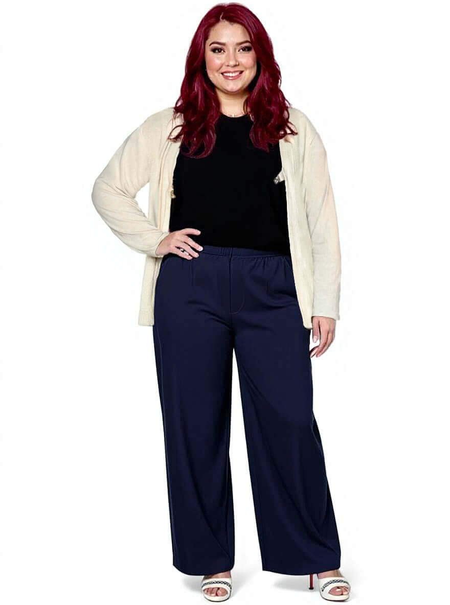Plus size woman wearing Dale and Waters Mercedes E2E Cardi in Stone with navy wide-leg pants.