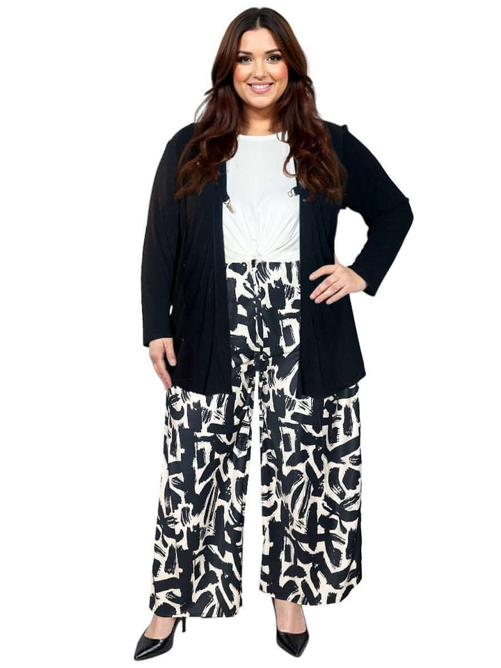 Plus size woman wearing a black Mercedes E2E Cardi, styled with patterned wide-leg pants and a white top.