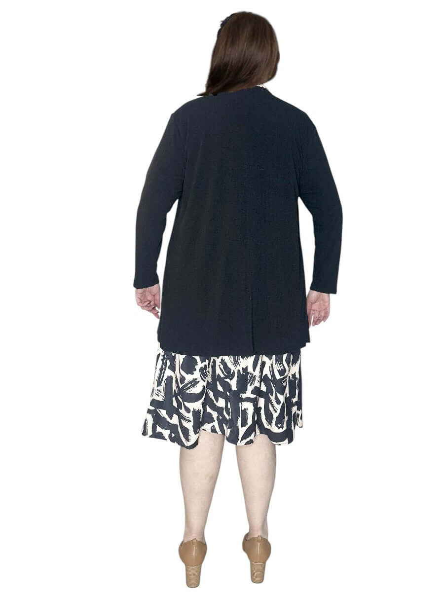 Back view of a woman wearing a plus size black Mercedes E2E Cardi paired with a patterned skirt.