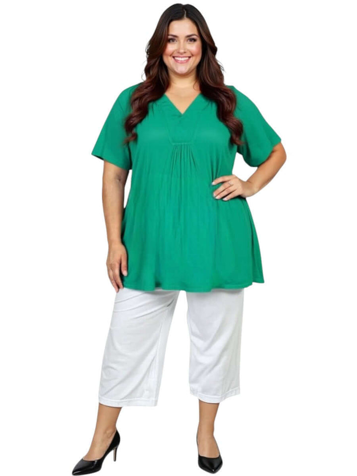 Plus size woman wearing Love Is In The Air Pants - White, styled with a green top, perfect for summer comfort.