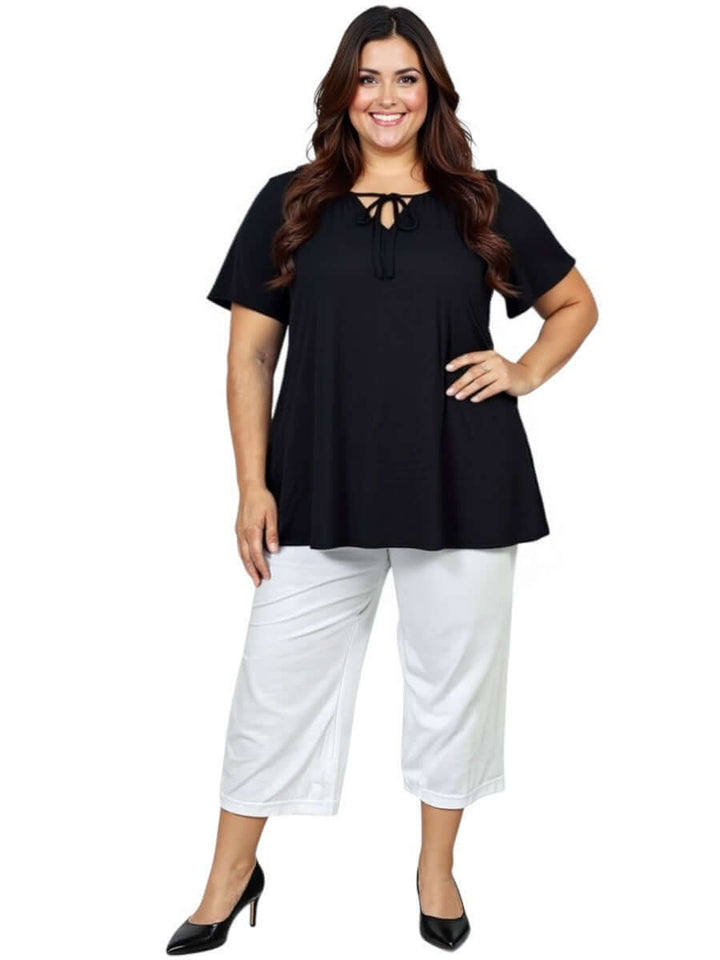 Plus size woman wearing Love Is In The Air Pants - White with a black top and heels, showcasing stylish summer comfort.