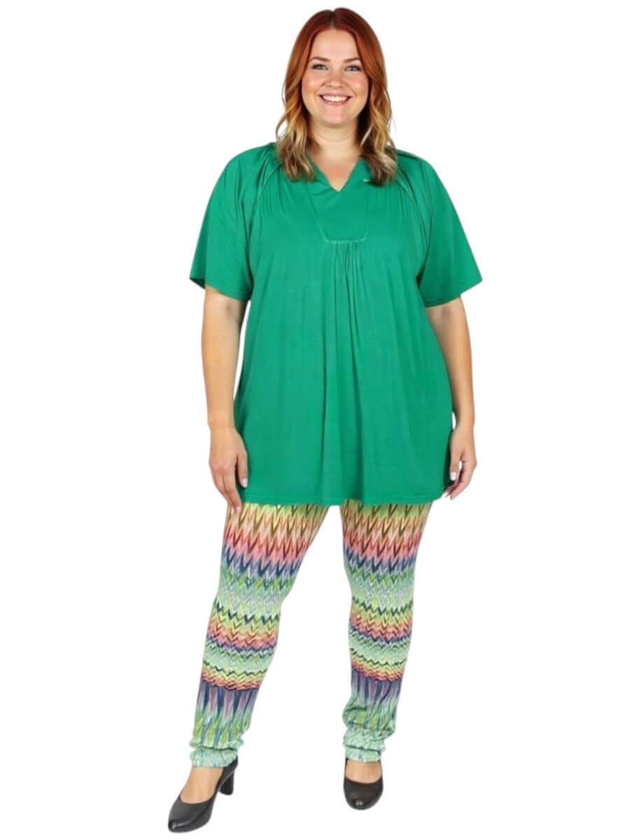 Atlas Leggings - Multi Print worn by plus size woman in vibrant pattern, paired with a green tunic, showcasing effortless style.