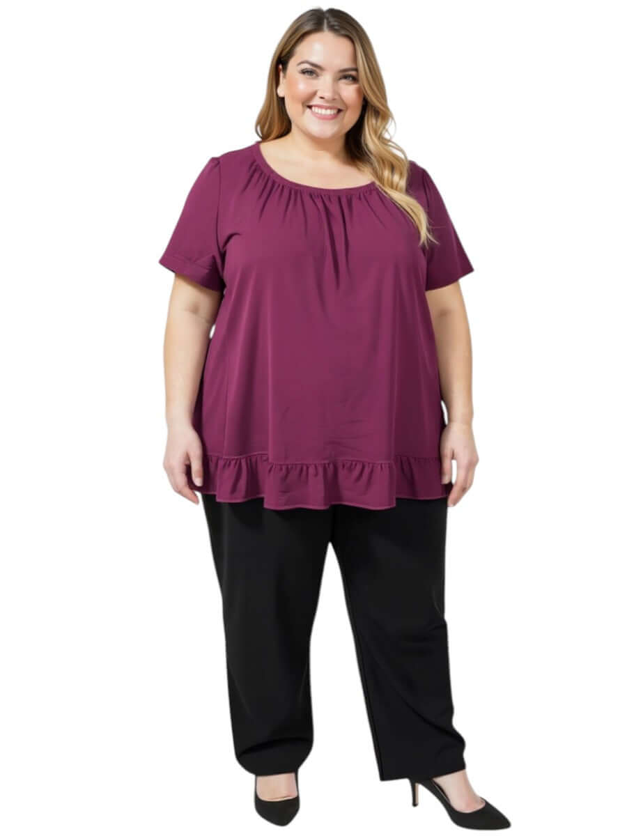 Women’s Plus Size Landra Top - Plum with flutter sleeves and ruffled hem, styled with black pants.