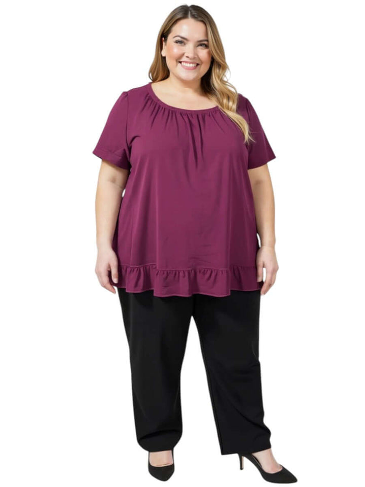 Women’s Plus Size Landra Top - Plum with flutter sleeves and ruffled hem, styled with black pants.