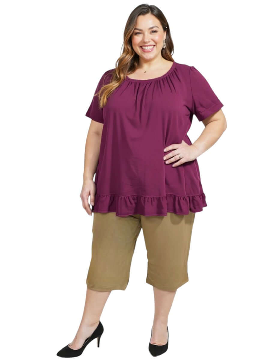 Women’s Plus Size Landra Top - Plum, featuring a gathered neckline and ruffled hem, paired with casual capris.