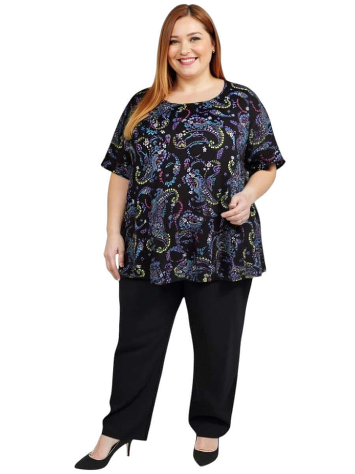 Estela Top - Black Print worn by a plus-size woman, featuring a flowy design with colorful patterns and short sleeves.