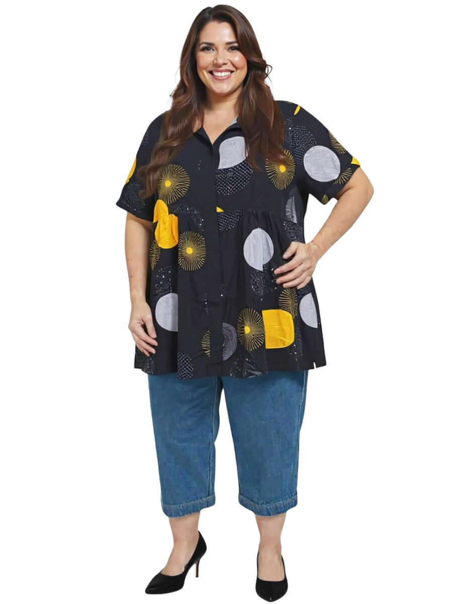 Coreen Tunic - Black Print worn by plus-size model, showcasing a babydoll blouse with vibrant circular print.