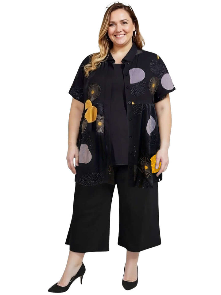 Coreen Tunic - Black Print worn by a plus-size woman, featuring vibrant prints, relaxed fit, and classic collared neckline.