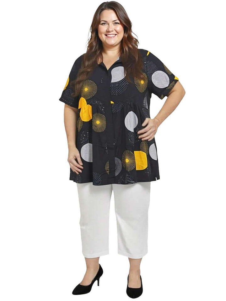 Coreen Tunic - Black Print on a model, featuring a babydoll design with vibrant yellow and grey polka dots, plus size comfort.