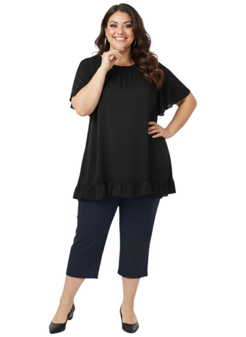 Landra Top - Black worn by a plus size woman, showcasing flutter sleeves and ruffle hem in an elegant, comfortable fit.
