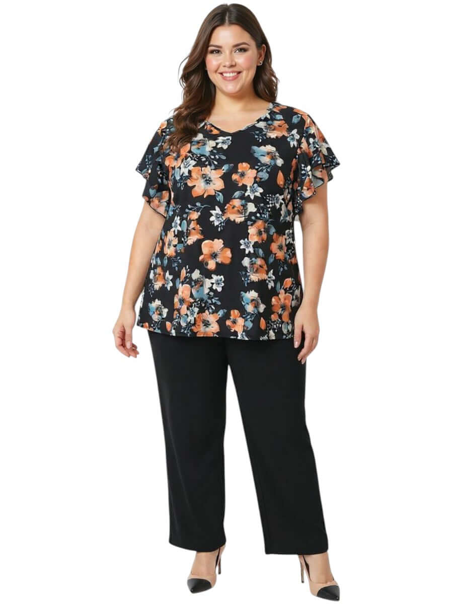 Women in a plus size floral blouse, showcasing the Kerissa Top - Black Print, paired with black trousers.