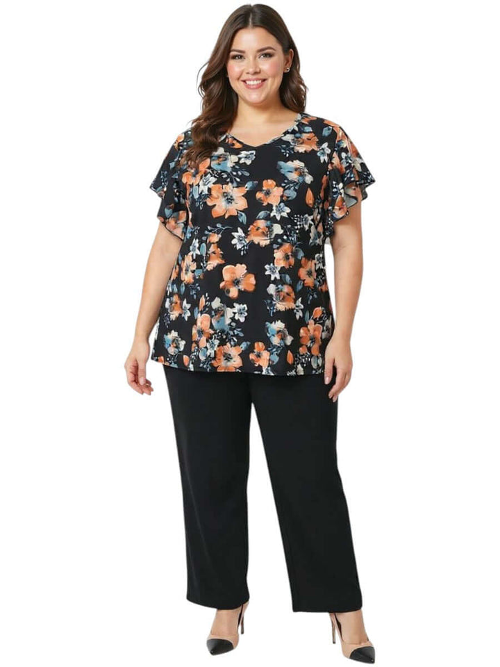 Women in a plus size floral blouse, showcasing the Kerissa Top - Black Print, paired with black trousers.