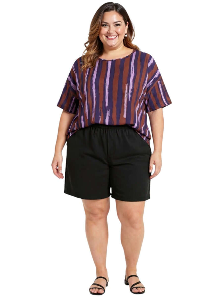 Model wearing the Velma Top - Purple Print with black shorts, showcasing women's plus size fashion.