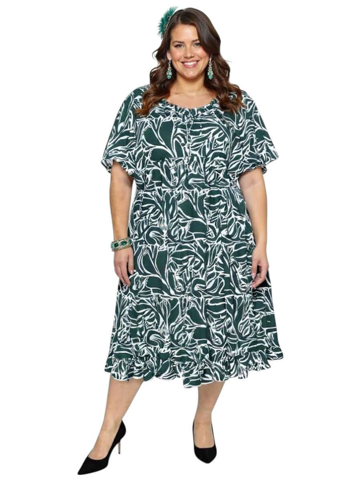 Plus size model wearing a green print Trinity Dress with pleated ruffle and tie detail by Dale and Waters.