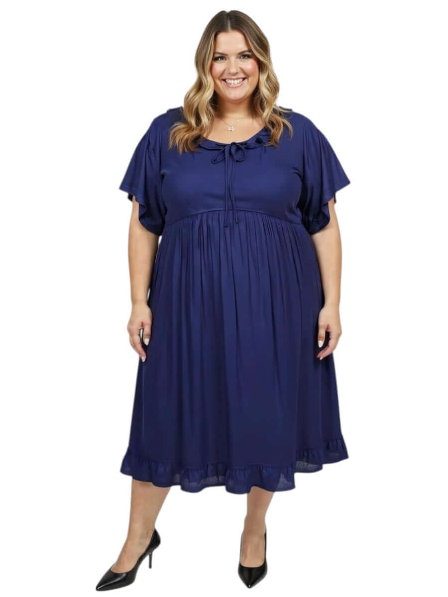 Plus size woman wearing the Dale and Waters Trinity Dress in navy, featuring a round neckline and pleated ruffle.