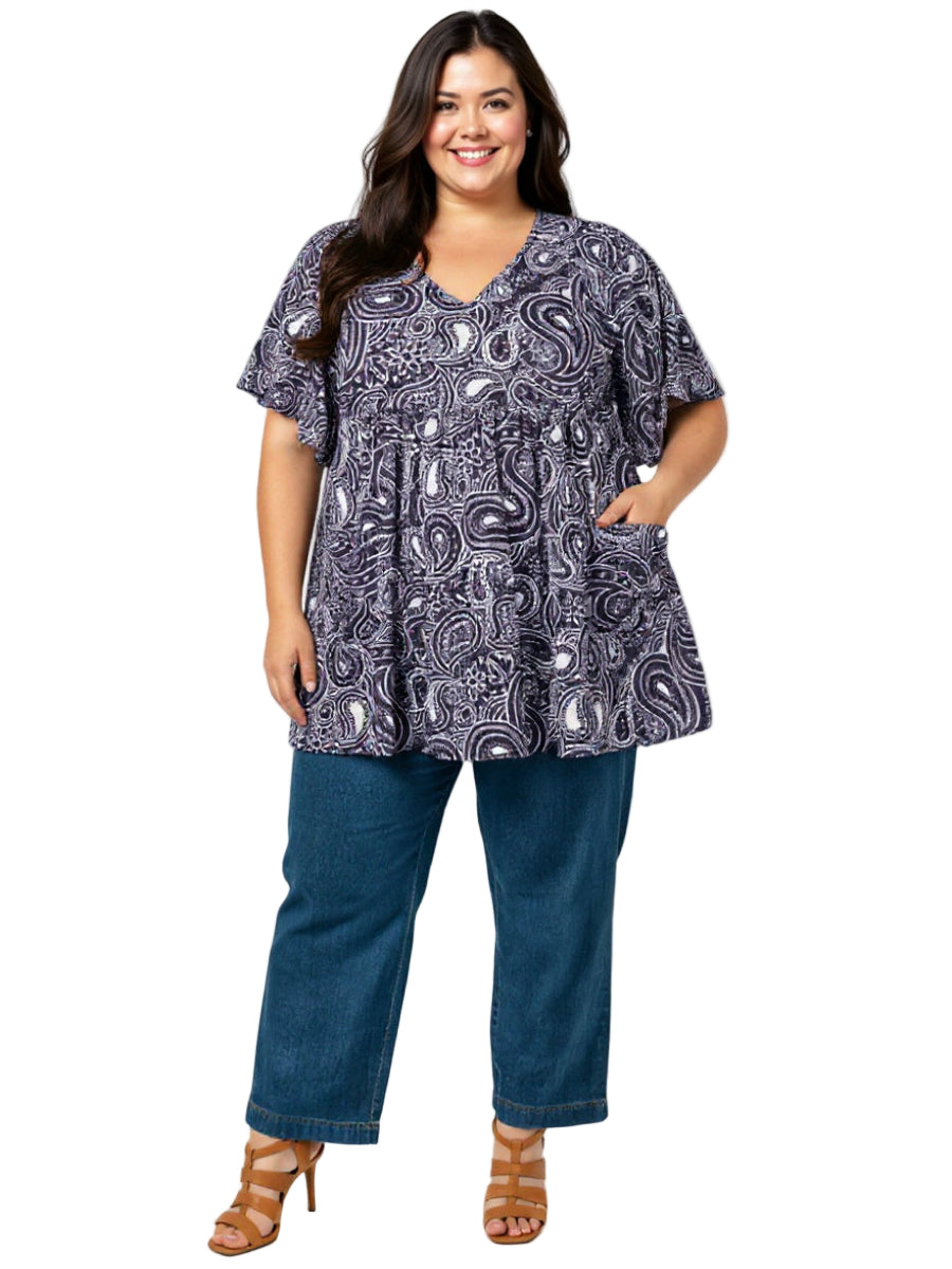 plus size Woman wearing a paisley patterned top and blue jeans on a white background