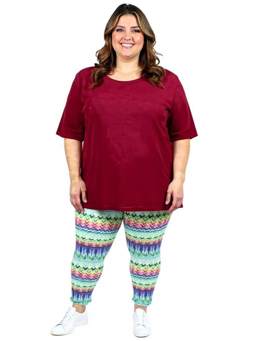 Atlas Leggings - Multi Print worn by a plus size woman in colorful pants and a maroon top.