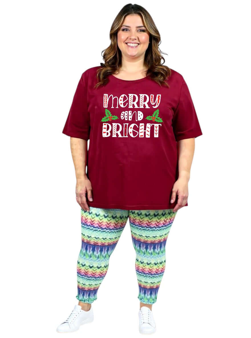 Women in Plus Size Atlas Leggings - Multi Print, wearing a Merry and Bright shirt, showcasing vibrant holiday style.