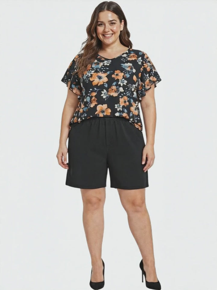 Kerissa Top - Black Print worn by a plus size woman, featuring a floral design and paired with black shorts.