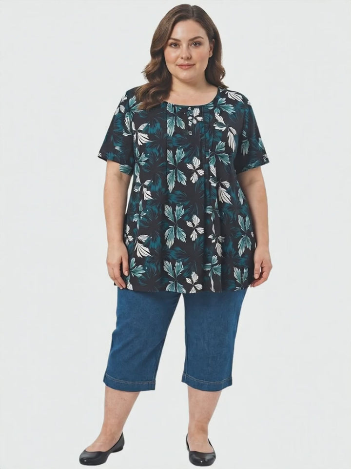 Rainer Top - Teal Print worn by plus size woman, featuring botanical leaf print in teal and white on black background.