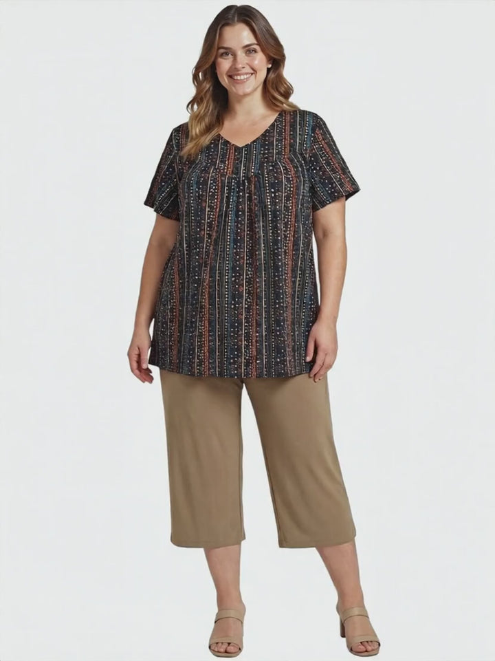 Fernando Top - Black Print worn by a plus-size woman, showcasing a vibrant boho design with geometric stripes.